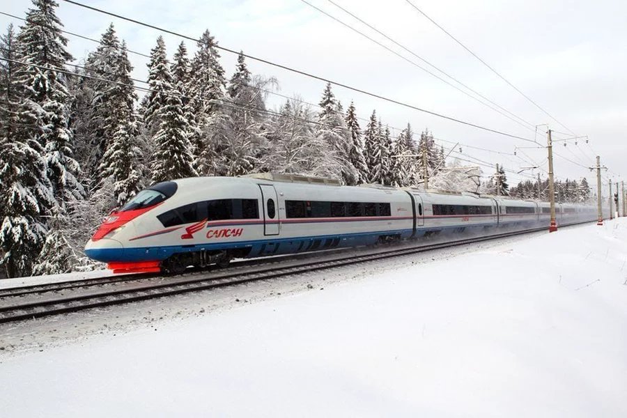 Le train à grande vitesse Sapsan longeant une forêt de sapins enneigés, entre Moscou et Saint-Pétersbourg